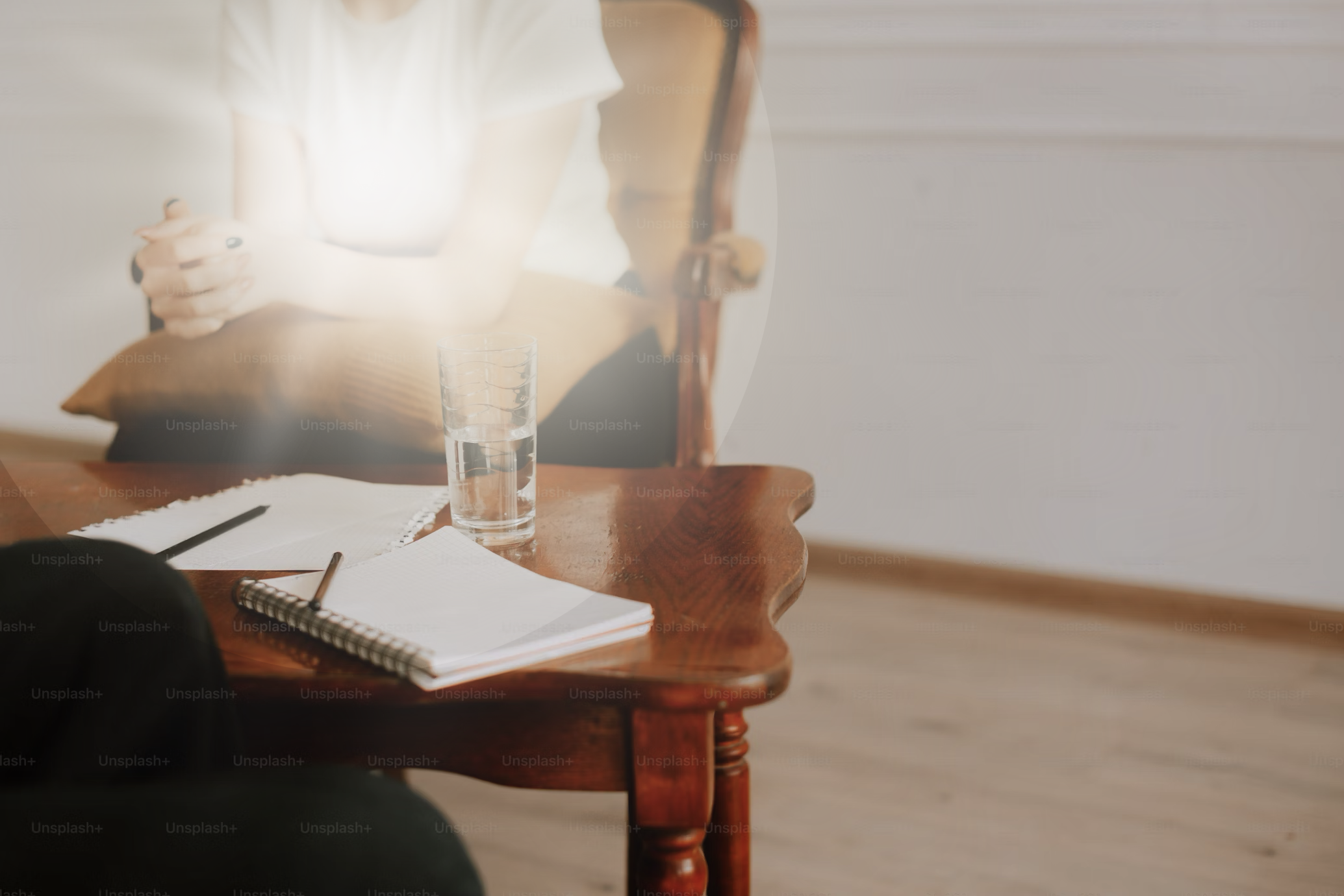 A photo of a desk with a person sitting while writing with a bright light shining from their midsection creating a focal point of hope.
