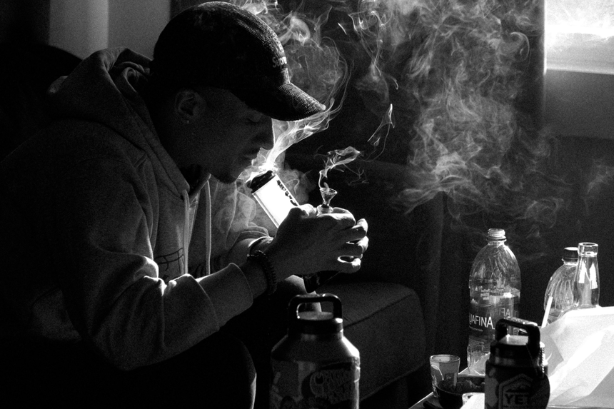 black and white photo of a young man smoking from a bong. 